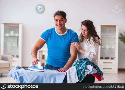 Man husband ironing at home helping his wife