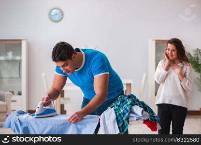 Man husband ironing at home helping his wife