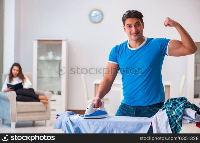 Man husband ironing at home helping his wife