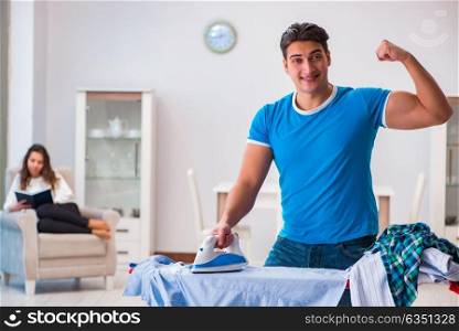 Man husband ironing at home helping his wife