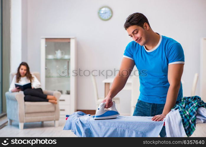 Man husband ironing at home helping his wife