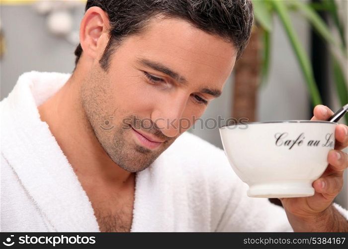 Man in a bathrobe with a cup of coffee and a pen