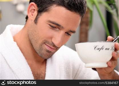 Man in a bathrobe with a cup of coffee and a pen