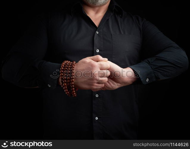 man in a black shirt crossed his arms in front of the torso, performing mudra, meditation