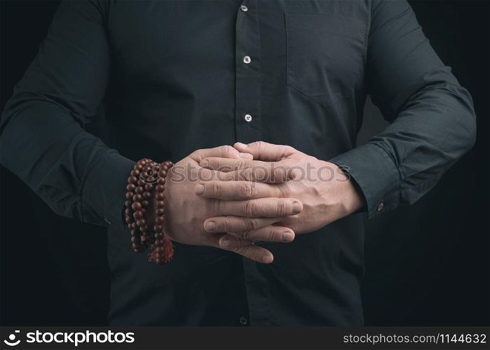 man in a black shirt crossed his arms in front of the torso, performing mudra, meditation