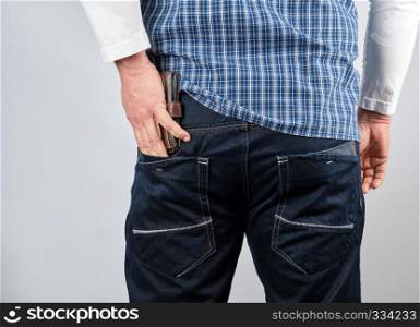 man in a blue plaid shirt and jeans puts a leather wallet in his back pocket, white background