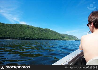 man in a boat on the background of the river and mountains