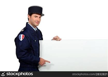 Man in a French gendarme uniform pointing at a blank board ready for text or image
