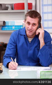 Man in a plumber&rsquo;s merchants taking an order on the telephone