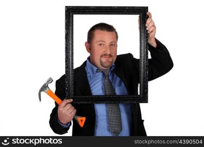Man in a suit with a picture frame and hammer