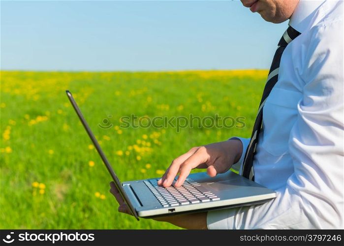 man in a tie with laptop in nature
