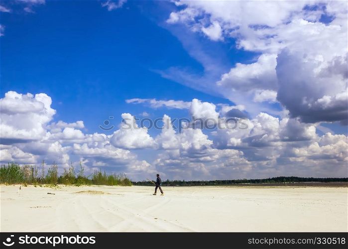Man in a turban walking on sandy plains under a sky with cumulus clouds on a sunny day.. Man In The Turban Walking Under a Cloudy Sky