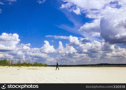 Man in a turban walking on sandy plains under a sky with cumulus clouds on a sunny day.. Man In The Turban Walking Under a Cloudy Sky