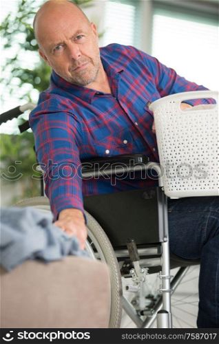 man in a wheelchair holding cloth basket