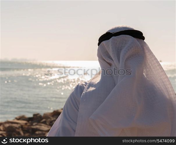 Man in Arab dress looks at the sea