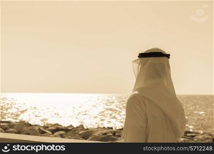 Man in Arab dress looks at the sea. Toned