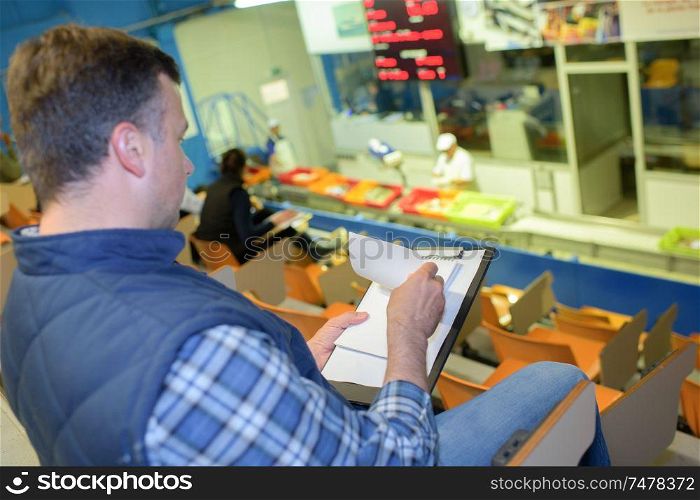 Man in auctionhouse looking through paperwork