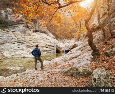 Man in autumn forest and river. Landscape and nature scene.