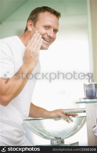 Man in bathroom applying shaving cream and smiling