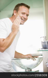 Man in bathroom applying shaving cream and smiling