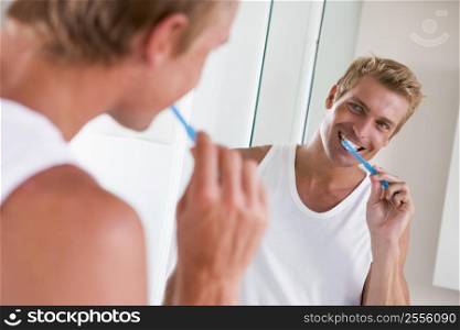 Man in bathroom brushing teeth and smiling