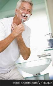 Man in bathroom shaving and smiling