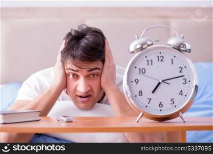 Man in bed frustrated suffering from insomnia with an alarm cloc. Man in bed frustrated suffering from insomnia with an alarm clock