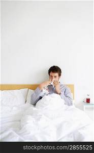 Man in Bed with a Cold Blowing His Nose