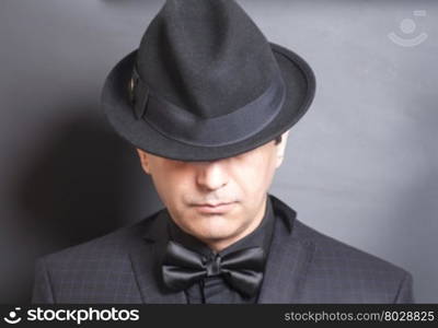 Man in black hat and black bowtie on gray background