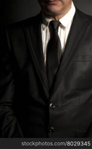 Man in black suit and black tie on a black background
