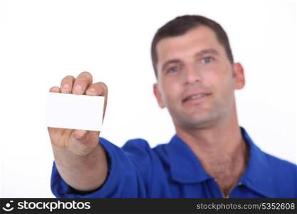 Man in blue overalls holding up a blank business card