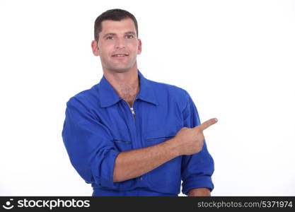 Man in blue overalls pointing