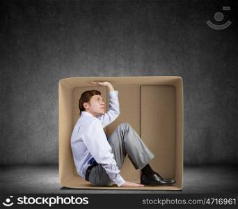 Man in box. Young frustrated businessman trapped in small carton box