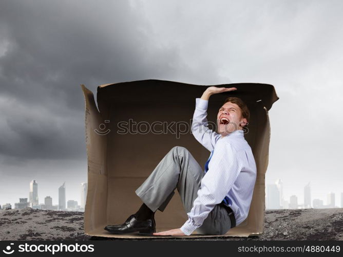 Man in box. Young frustrated businessman trapped in small carton box