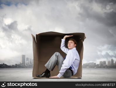 Man in box. Young frustrated businessman trapped in small carton box