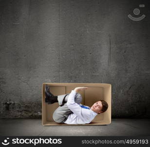 Man in box. Young frustrated businessman trapped in small carton box