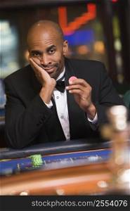Man in casino playing roulette and holding chip (selective focus)