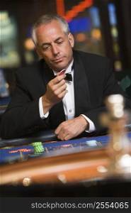 Man in casino playing roulette and looking at chip (selective focus)