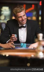 Man in casino playing roulette and smiling (selective focus)