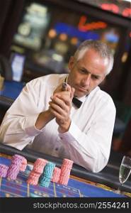 Man in casino playing roulette and smoking cigar (selective focus)