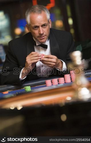 Man in casino playing roulette holding chips (selective focus)