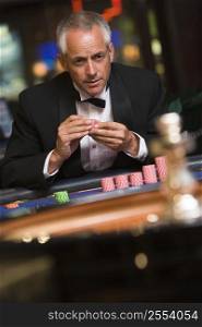 Man in casino playing roulette holding chips (selective focus)