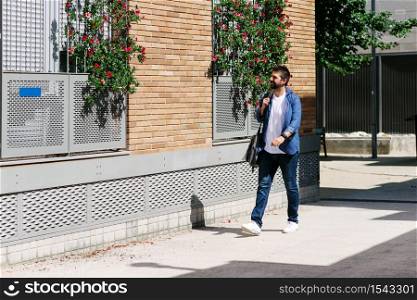 Man in casual clothes walking in the street while holding a shoulder bag