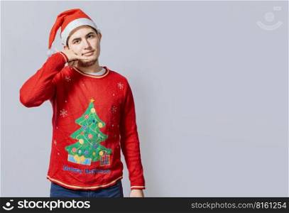Man in christmas clothes imitating a phone conversation, Young latin man in christmas hat making a call gesture isolated. People in Christmas clothes making a call gesture with their fingers