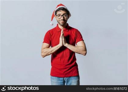 Man in christmas hat with hands together making a wish isolated. Guy with hands together making a christmas wish, Concept of christmas hat person making a wish