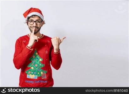Man in Christmas sweater in silence gesture pointing to the side, Guy in Christmas hat with finger on lips pointing side. Bearded man in christmas hat in silence gesture pointing promo