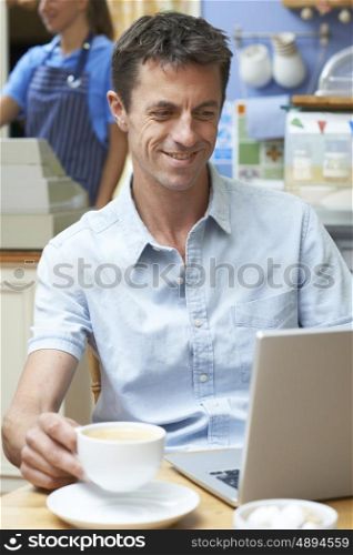 Man In Coffee Shop Using Laptop Computer