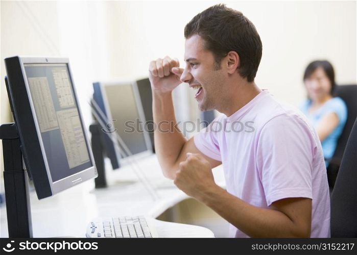 Man in computer room cheering and smiling