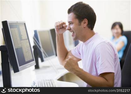 Man in computer room cheering and smiling