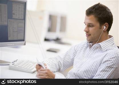 Man in computer room listening to MP3 player